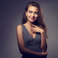 Beautiful romantic woman in fashion strip dress and bright makeup looking up with positive emotional face and thinking about Christmas gift. Closeup toned portrait