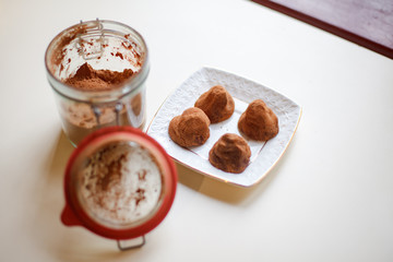 handmade candy made from carob or cocoa, lie on a white plate, next to a jar of carob or cocoa
