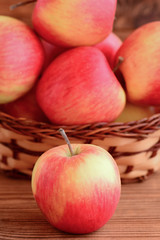 Raw red apples on a wooden table and in a basket. Sweet apples photo. Diet dessert. Vertical photo. Closeup