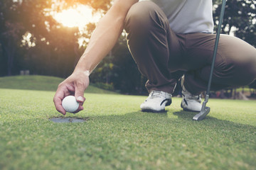 Golfers keep the golf ball up from the hole. lens flare on sun set evening time. Concept of success.