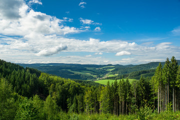 Endless wide scenic view on black forest landscape with blue sky and small village far away