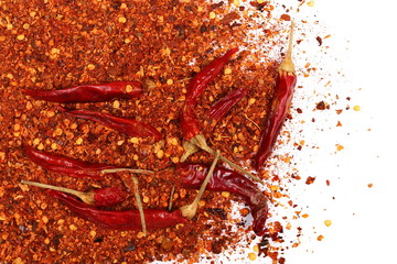 Dry red hot chili peppers with flakes, pile isolated on white background, top view