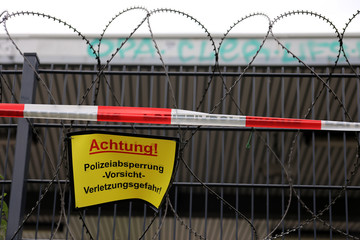 Zaun mit Polizeiabsperrung und NATO-Stacheldraht