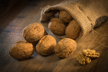 Walnut kernels and whole walnuts on rustic old oak table