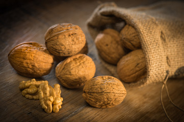 Walnut kernels and whole walnuts on rustic old oak table