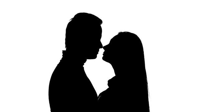 Kissing couple in the studio is worth it. Silhouette. White background. Close up