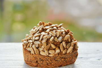 Freshly baked raisins cake with sunflower seeds isolated on gray wooden table. Muffin on blurred nature background. Close up view
