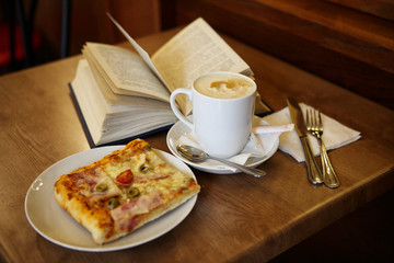 Cup of coffee with a pizza on the table in the cafe