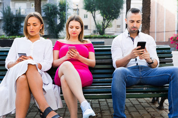 Obraz premium Young people are focusing on smartphones during a together walking outdoors.