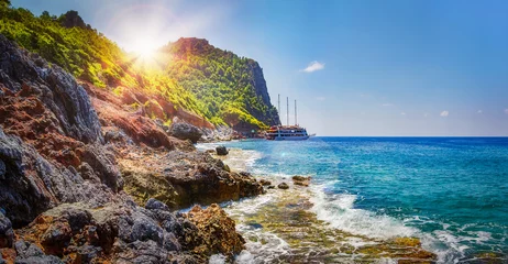 Foto auf Alu-Dibond Tropical rocky beach on sunny summer day in Alanya, Turkey. Sea and mountains landscape with waves. Lagoon bay. Panoramic view on paradise coastline. Summer vacation nature. Adventure and travel. © dzmitrock87