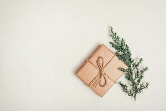 gift, a surprise in the box is packed in brown vintage paper and tied with a rope, scoop. Christmas concept. on a white homogeneous background. near a branch of a coniferous tree