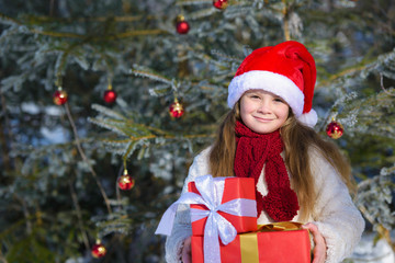 Adorable  little girl with christmas gifts im winter forest