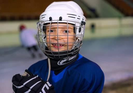 A boy plays hockey on the ice area. Boy seven years.