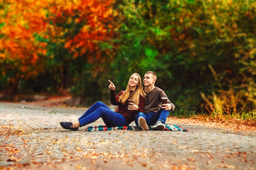 Fototapeta premium the couple is sitting on a blanket. walk in the street. autumn day. hot coffee. look somewhere