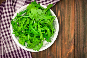 Fresh juicy leaves of arugula on a brown wooden table.