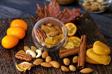 Mix dried fruits and nuts almonds, pecans, cashew nuts, dried grapes, oranges, kumquat, cinnamon sticks on a wooden background. Close-up