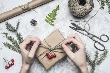 girl wraps a gift for a new year or Christmas, next to it is a roll of paper, vintage scissors,...