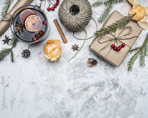 Christmas concept, mulled wine and ingredients for its preparation, packing paper, string, gift in a box, tangerines, cinnamon sticks, on a white rustic background, space for text