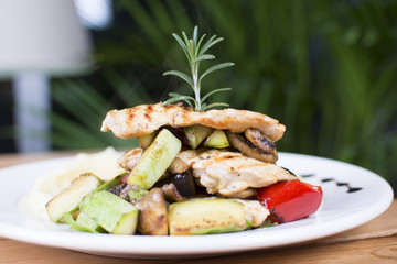 Grill chicken breast. Grilled vegetables with chicken breast. Grilled chicken with vegetables on oak table.