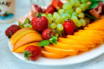 Fresh fruits and berries of different bright colors cut in small pieces are served on a table in restourant