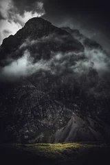 Fototapeten Dark, stormy shrouded mountain with light at base © XtravaganT