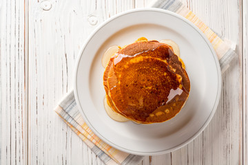 Pumpkin pancakes with honey in plate on white wooden background. © nesavinov