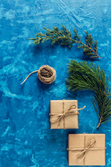 gift, a surprise in the box is packed in brown vintage paper and tied with a rope, scoop. Christmas concept. on a blue homogeneous background. near a branch of a coniferous tree