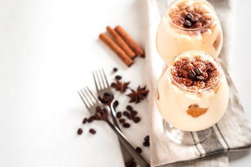 Exquisite Italian dessert tiramisu in cognac glasses on a white