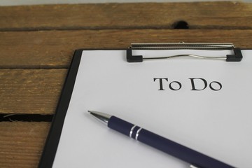 To Do Liste mit stift auf Klemmbrett vor Holz
