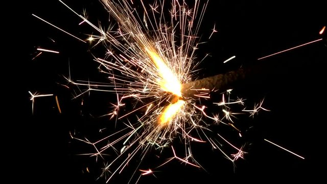 Sparklers close and beautifully lit at night. Lights sparked and burned in his hands. Festive Sparkler close - an attribute of good mood.
