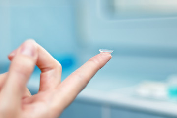 girl holds finger on a contact lens, closeup