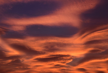 Strange and unusual cloud with spiral pink, orange, golden and blue at sunset in the sky of Turin, Italy.
