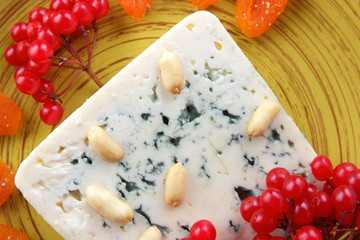 Cheese with mold, fruits and nuts on a dark blue background, cinnamon, buckwheat, red berries, pop art, minimalism, cheese with honey for Christmas, cheese on a plate on a dark blue background