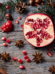 Fototapeta na wymiar Pomegranate spruce branches star anise nuts, cinnamon and winter spices on wooden background, Rustic style