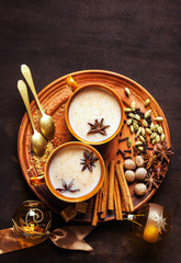 Obraz na płótnie Canvas Masala tea chai latte traditional hot Indian teatime ceremony sweet milk with spices, herbs organic infusion healthy beverage in porcelain cup on wooden table background. Christmas 