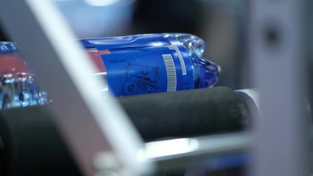 Labeling machine at water production line. Water products labeling at dairy factory. Close up packing water bottles. Label water bottles. Bottle label at dairy plant.