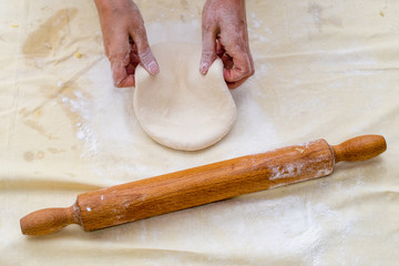 Female hands making dough for pizza, rolling pin on table