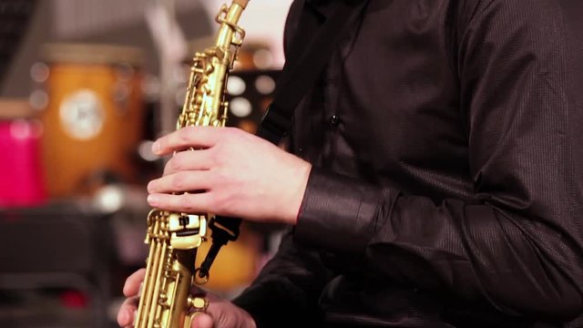 A man with a beard in a black shirt emotionally plays the soprano saxophone. Close-up.