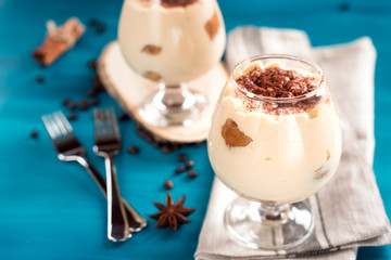 Luxurious, exquisite Italian dessert tiramisu in cognac glasseson a blue background