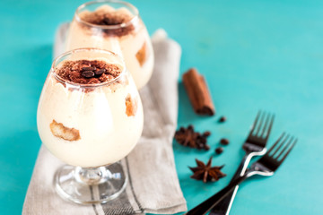 Luxurious, exquisite Italian dessert tiramisu in cognac glasseson a blue background