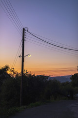 Vintage telegraph post with illuminating street lantern at sunset. Corfu, Greece.