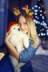 Happy girl in antler with samoyed husky dog in Christmas decorations