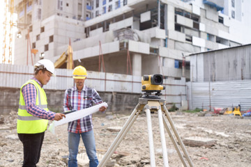 Asian civil engineer checking work for control and management in the construction site or building site of high rise building.