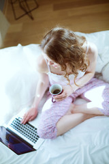 Young beautiful woman sitting in bed with laptop.
