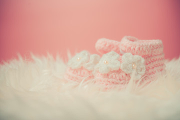 Close up Baby girl knitted shoes on white blanket background.Happy new year greeting card with copy-space. New born celebration holiday concept.