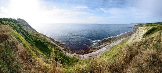 Beautiful view of seashore. Rocks, beach and sea against blue sky.