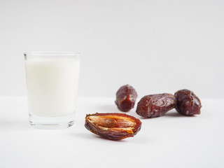Date fruit and a glass of milk on a white background.
