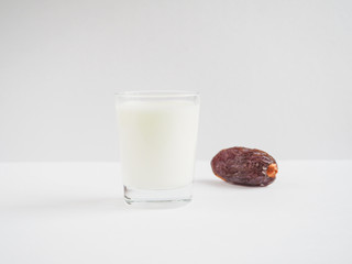 Date fruit and a glass of milk on a white background.

