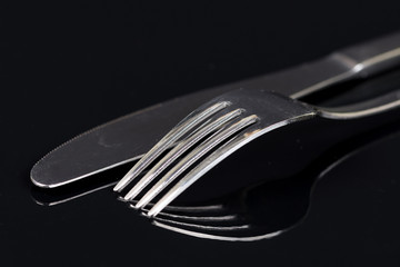 Silverware fork and knife on the black background with reflections