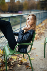 Young stylish woman tourist near the famous green chairs in Tuileries garden in Paris